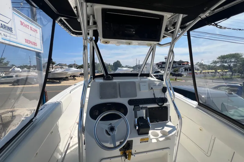 Slide: The Image of 2002 Triton 2895 CC boat cockpit with steering wheel and control panel, docked near marina. - 21