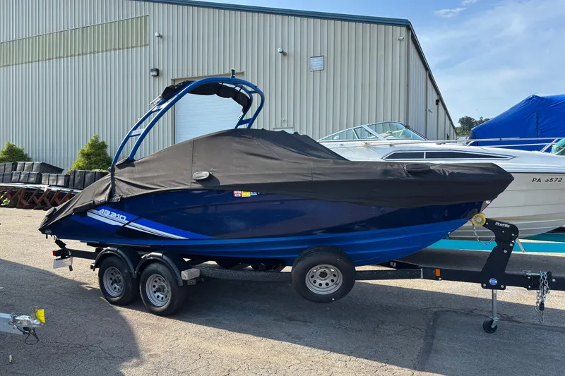 Slide: The Image of 2020 Yamaha AR210 boat covered on trailer, parked outside a warehouse. - 13
