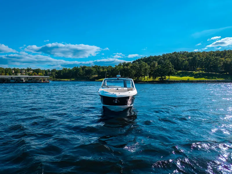 Slide: The Image of Cruisers Yachts 42 GLS 2027 on a calm lake with a wooded shoreline in the background. - 24