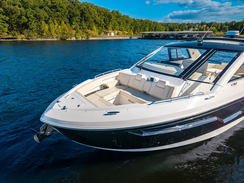 Slide: The Image of The 2027 Cruisers Yachts 42 GLS glides on a calm lake with a wooded shoreline in the background. - 9