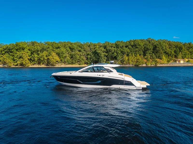Slide: The Image of The 2027 Cruisers Yachts 42 GLS glides on calm waters, surrounded by lush trees. - 3