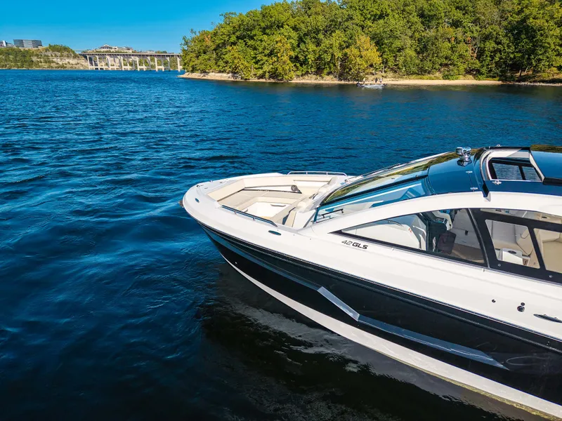 Slide: The Image of 2027 Cruisers Yachts 42 GLS on a calm lake with a wooded shoreline in the background. - 14