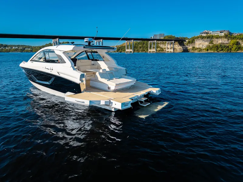 Slide: The Image of Cruisers Yachts 42 GLS 2027 on calm water with a bridge in the background. - 1
