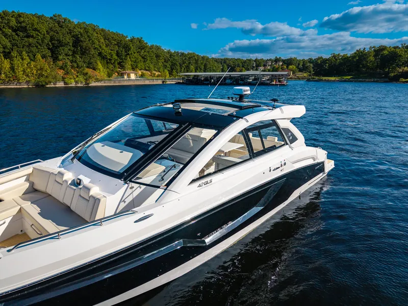 Slide: The Image of The 2027 Cruisers Yachts 42 GLS on a calm lake with a wooded shoreline. - 10