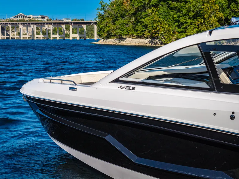 Slide: The Image of The 2027 Cruisers Yachts 42 GLS is on calm waters with a bridge in the background. - 13