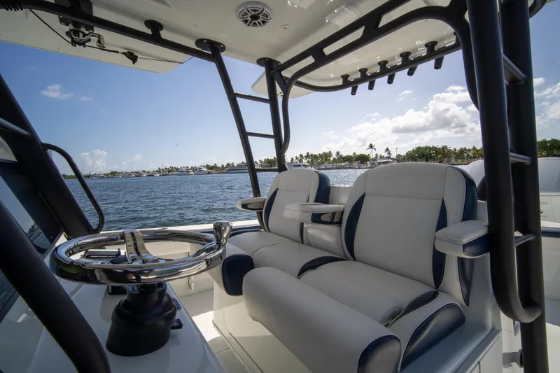 Slide: The Image of 2022 Yellowfin 39 Offshore boat interior with steering wheel and seating, overlooking calm waters. - 19