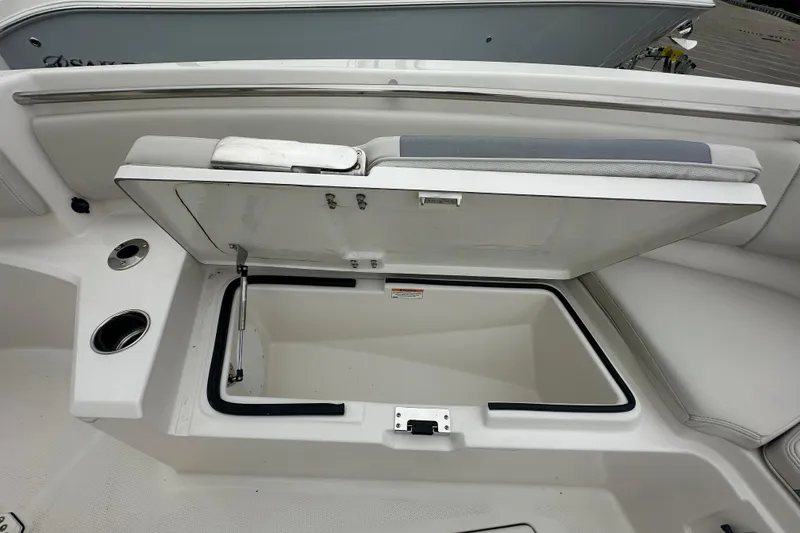 Slide: The Image of Open storage compartment on 2026 Sailfish 232 CC boat, featuring cup holders and cushioned seating. - 27