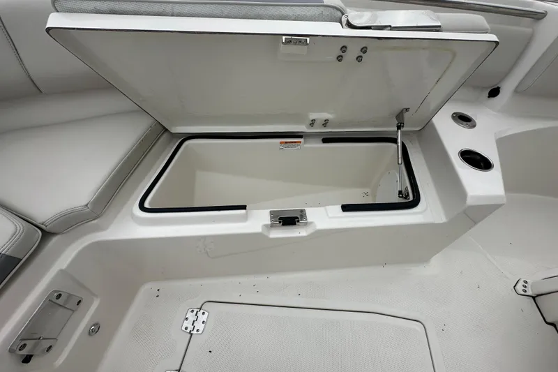 Slide: The Image of Open storage compartment on 2026 Sailfish 232 CC boat, featuring cup holders and cushioned seating. - 28