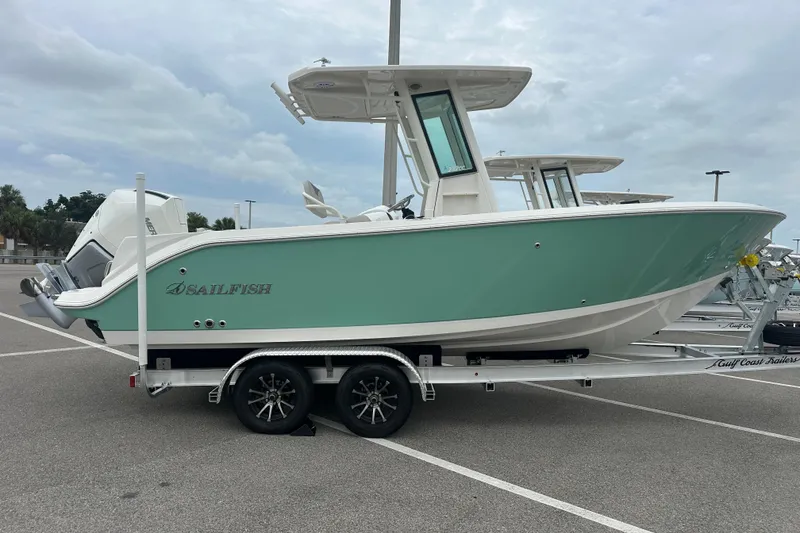 Slide: The Image of 2026 Sailfish 232 CC boat on trailer, parked in a lot under cloudy skies. - 13