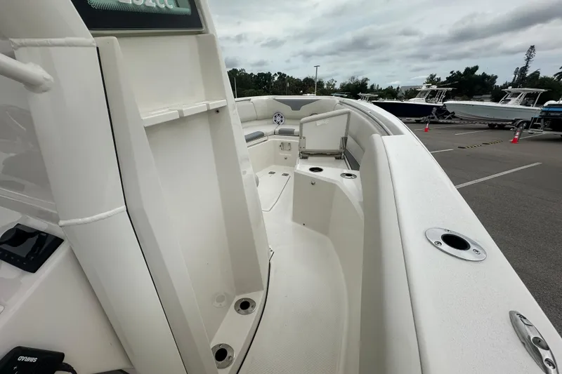 Slide: The Image of 2026 Sailfish 232 CC boat interior with seating and rod holders, parked outdoors. - 20