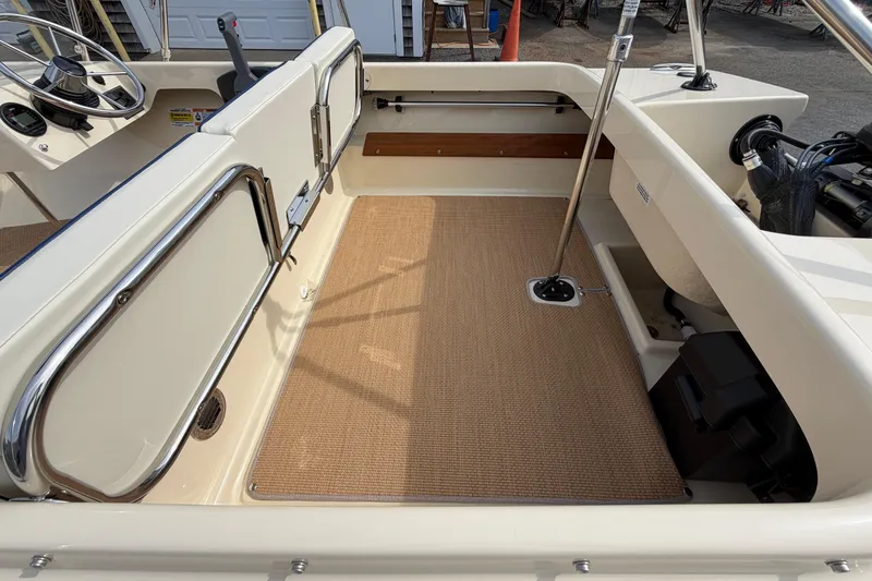 Slide: The Image of 2027 Rossiter 14 boat interior with beige flooring and stainless steel accents. - 14