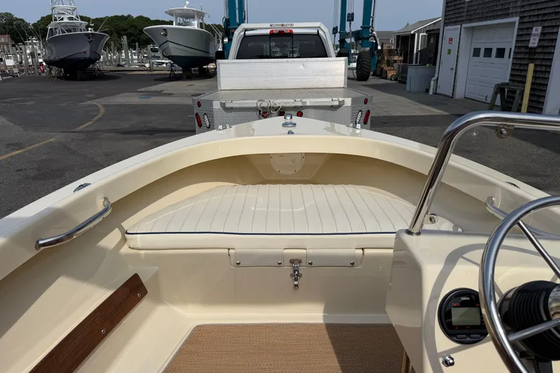Slide: The Image of 2027 Rossiter 14 boat interior with white seating, parked near marina. - 26