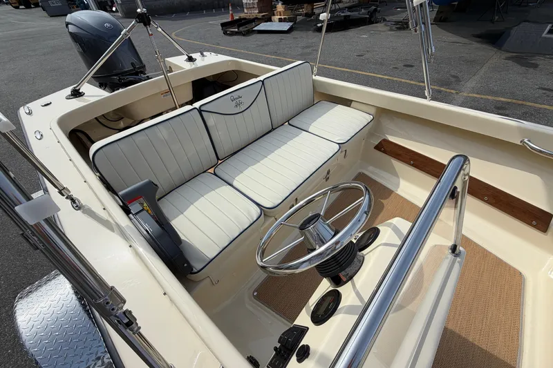 Slide: The Image of 2027 Rossiter 14 boat interior with white cushioned seating and steering wheel. - 18