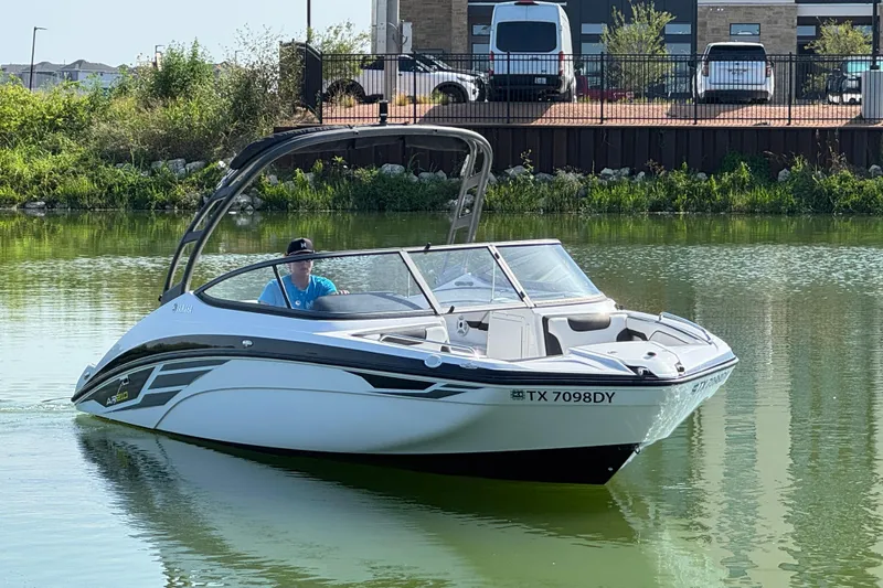 Slide: The Image of 2018 Yamaha AR210 boat cruising on a calm lake with a driver onboard. - 5