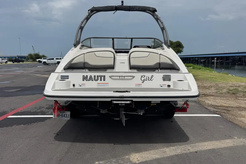 Slide: The Image of 2018 Yamaha Boats AR210, rear view, parked near water, with "Nauti Girl" text. - 10