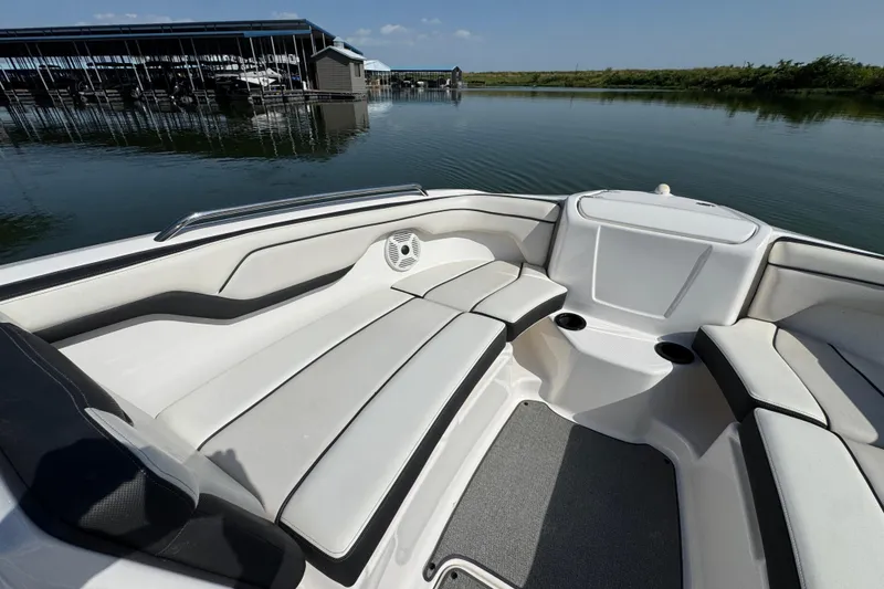 Slide: The Image of 2018 Yamaha Boats AR210 interior with white seating, docked by calm water. - 14