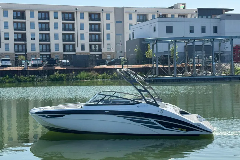 The Image of 2018 Yamaha AR210 boat on calm water, with modern buildings in the background. - 0