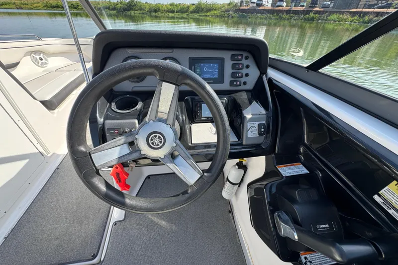 Slide: The Image of 2018 Yamaha Boats AR210 steering console with controls and display, overlooking calm water. - 17