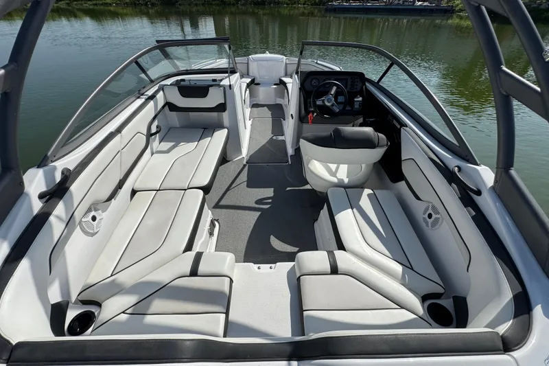 Slide: The Image of 2018 Yamaha Boats AR210 interior with sleek seating and modern dashboard on calm water. - 20