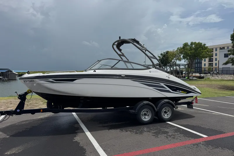 Slide: The Image of 2018 Yamaha Boats AR210 on trailer, parked near waterfront under cloudy sky. - 9