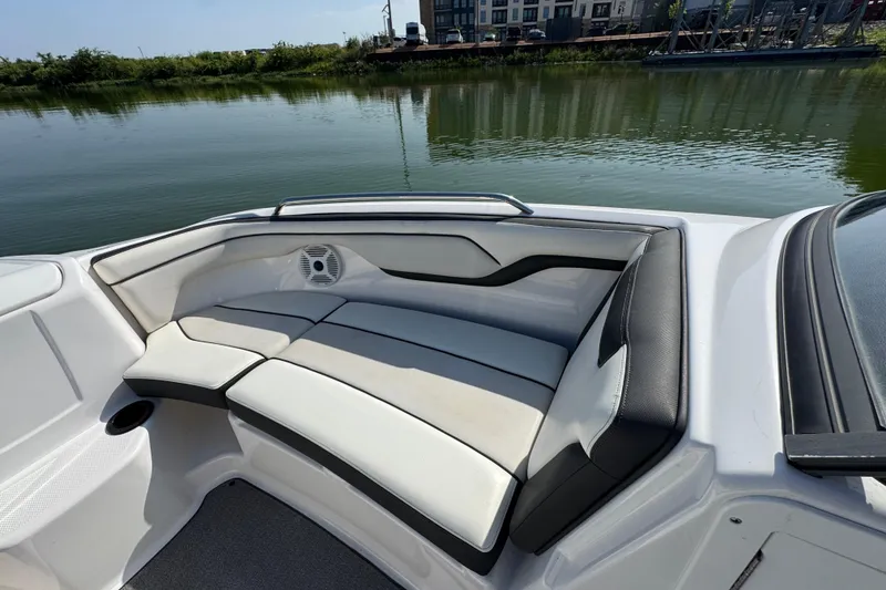 Slide: The Image of 2018 Yamaha AR210 boat interior with cushioned seating by calm water. - 13