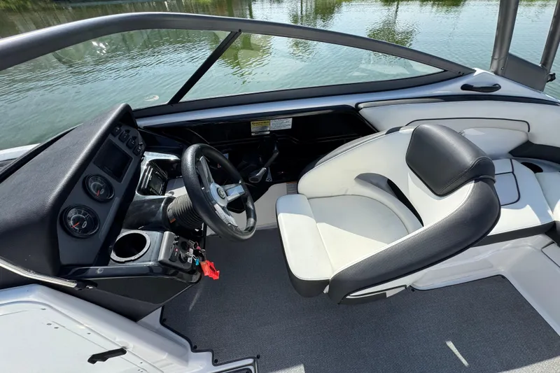 Slide: The Image of 2018 Yamaha Boats AR210 cockpit with steering wheel and seating, overlooking calm water. - 16