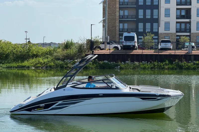 Slide: The Image of 2018 Yamaha AR210 boat on calm water near urban buildings. - 4