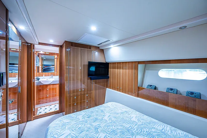 Slide: The Image of Luxurious 2009 Riviera 58 Flybridge yacht bedroom with wood paneling and modern amenities. - 26