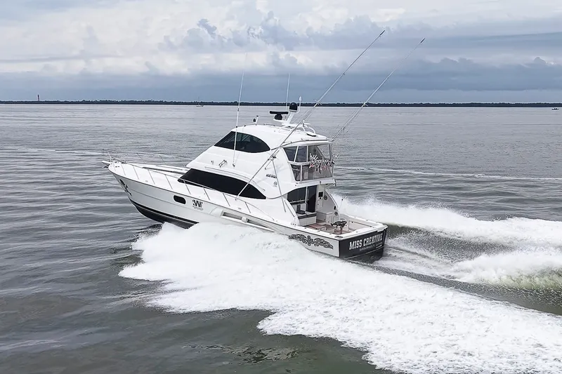Slide: The Image of 2009 Riviera 58 Flybridge yacht cruising on open water, creating a dynamic wake. - 93