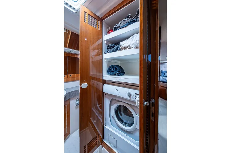 Slide: The Image of Laundry area with washer, shelves, and wooden cabinetry in a 2009 Riviera 58 Flybridge yacht. - 42