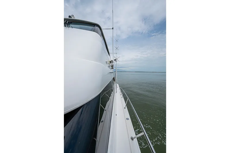 Slide: The Image of Side view of a 2009 Riviera 58 Flybridge yacht on calm waters under a cloudy sky. - 83