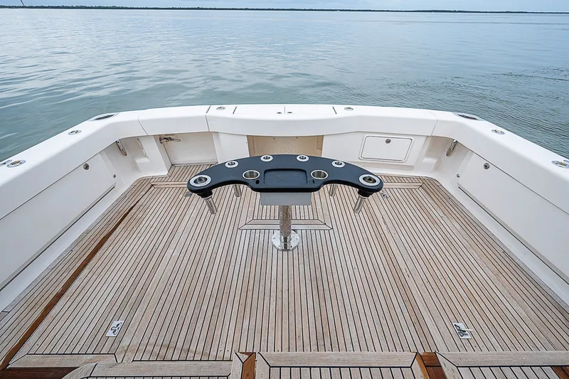 Slide: The Image of 2009 Riviera 58 Flybridge yacht deck with fishing rod holders, overlooking calm waters. - 70
