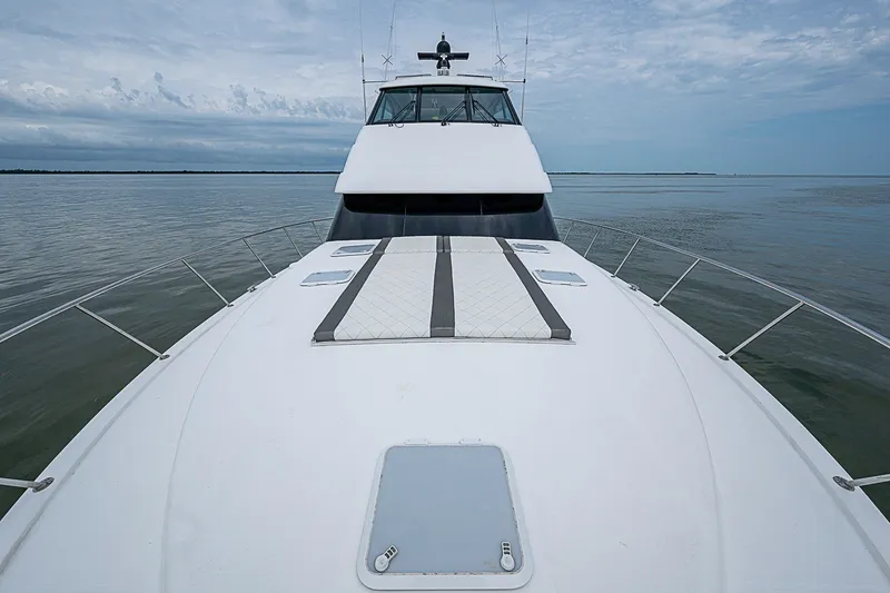 Slide: The Image of 2009 Riviera 58 Flybridge yacht on calm waters under a cloudy sky. - 90