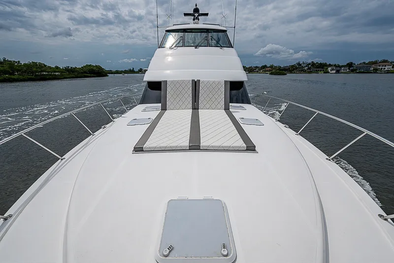 Slide: The Image of 2009 Riviera 58 Flybridge yacht cruising on a calm waterway under cloudy skies. - 86