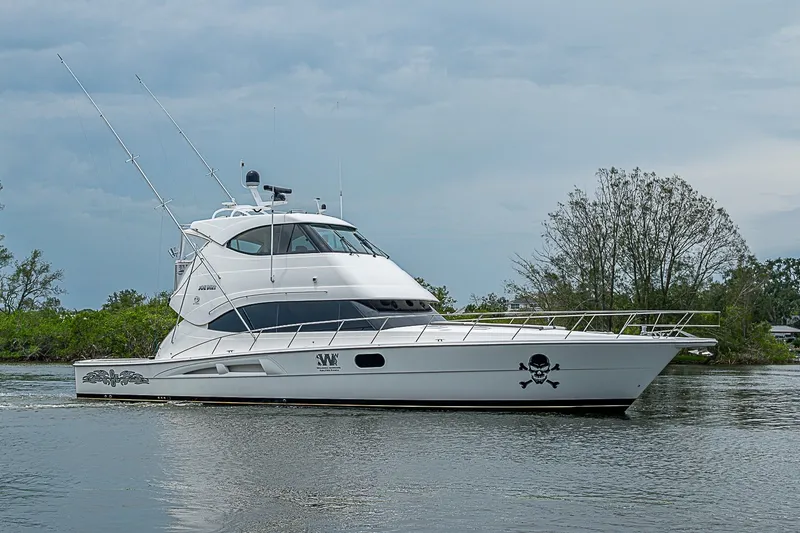 The Image of 2009 Riviera 58 Flybridge yacht cruising on a calm river with lush greenery. - 0