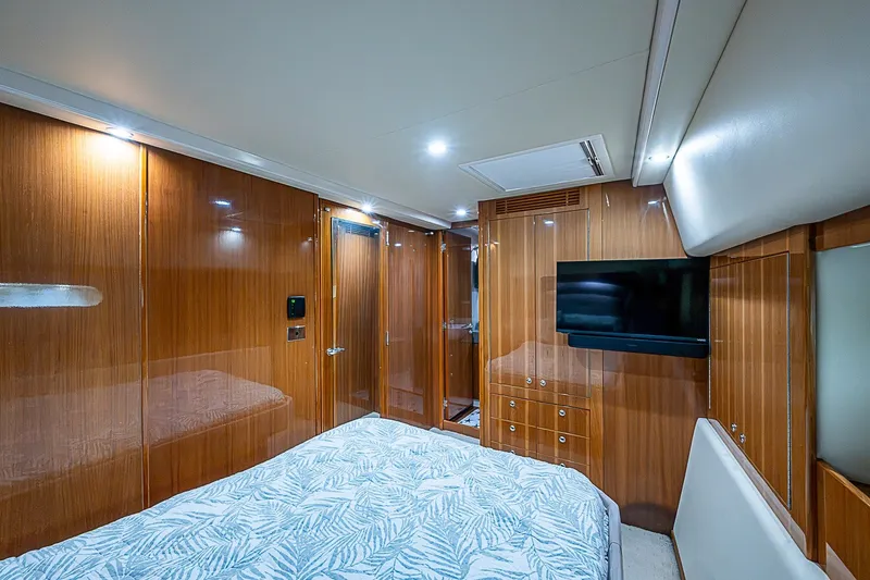 Slide: The Image of Luxurious 2009 Riviera 58 Flybridge yacht bedroom with wood paneling and mounted TV. - 25