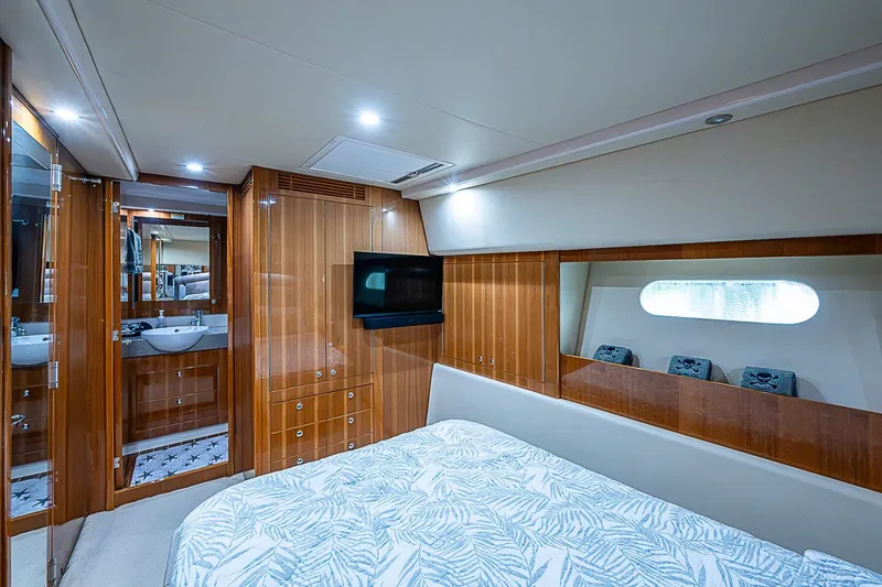 Slide: The Image of Luxurious 2009 Riviera 58 Flybridge yacht bedroom with wood paneling and ensuite bathroom. - 24