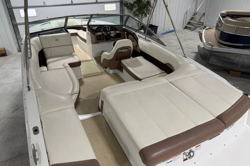 Slide: The Image of 2013 Cobalt 220 boat interior with beige and brown seating in a garage setting. - 4