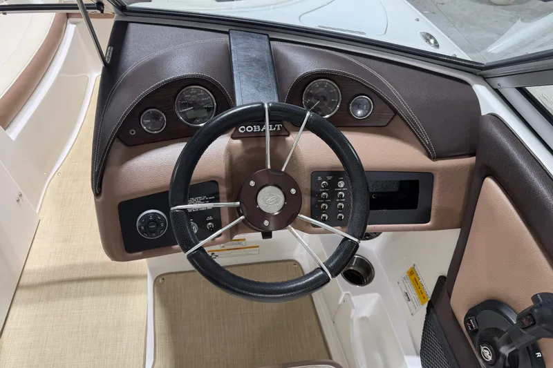 Slide: The Image of Steering wheel and dashboard of a 2013 Cobalt 220 boat, featuring gauges and controls. - 10