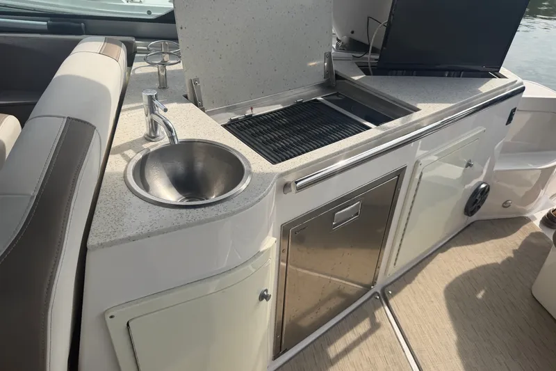 Slide: The Image of 2017 Regal 32 Express boat kitchenette with sink, grill, and storage cabinets. - 24