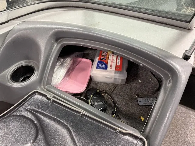Slide: The Image of An open storage compartment in a boat with fishing gear and a remote control. - 15