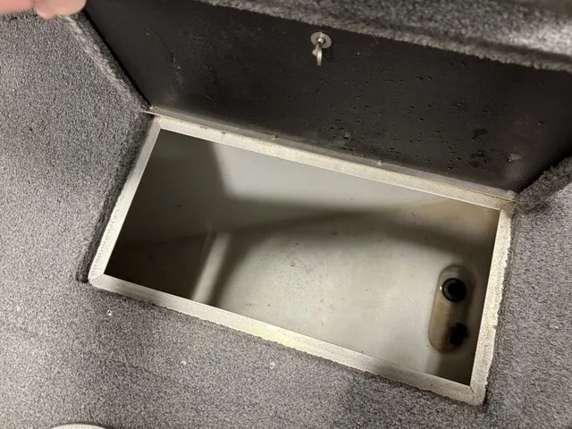 Slide: The Image of An open storage compartment in the floor of a boat with gray carpeting. - 24