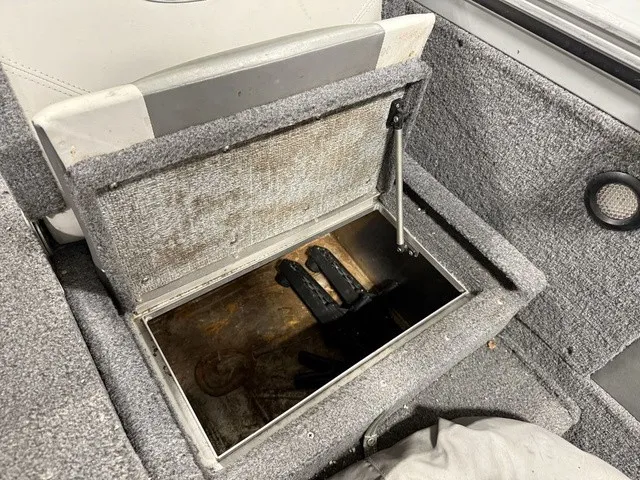 Slide: The Image of An open storage compartment in a boat with gray carpeting and a black object inside. - 18