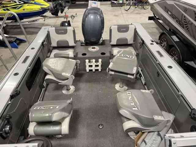 Slide: The Image of Interior view of a 2006 Lund 1800 Fisherman boat with four cushioned seats and an outboard motor. - 25