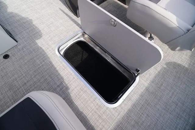 Slide: The Image of An open storage compartment on a boat with gray carpet flooring. - 24