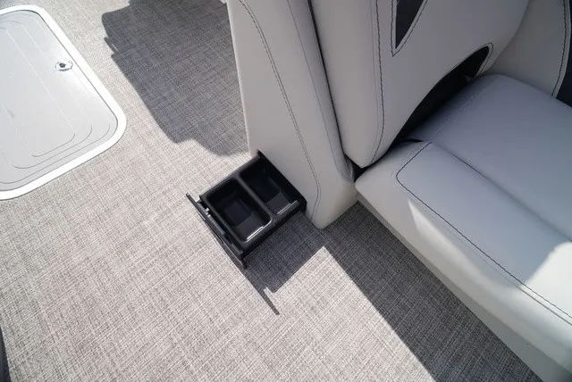 Slide: The Image of A gray boat seat with a pull-out cup holder on a textured floor. - 32