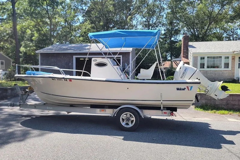 Slide: The Image of 1978 Wellcraft V-20 Steplift boat with blue canopy on trailer, parked in residential area. - 10