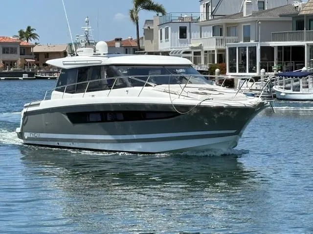 The Image of 2013 Jeanneau NC11 yacht cruising near waterfront homes. - 1