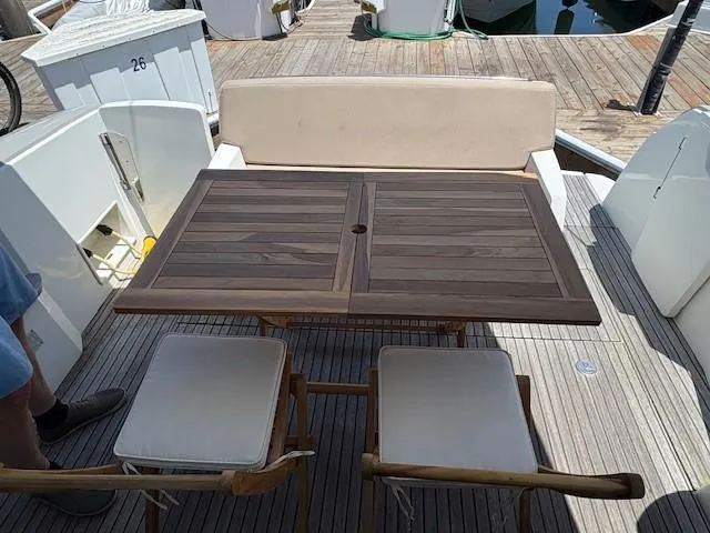 Slide: The Image of Outdoor seating area on a 2013 Jeanneau NC11 yacht with wooden table and cushioned chairs. - 2