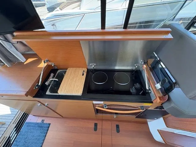 Slide: The Image of 2013 Jeanneau NC11 yacht kitchen with stove, sink, and wooden cabinetry. - 6